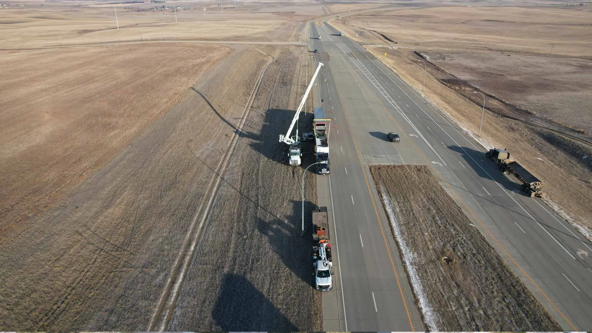 Aerial view of a boom truck and haul trucks working a highway right-of-way